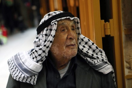 A Palestinian man wearing Keffiyeh walks at a street in the West