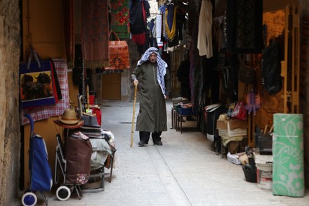 A Palestinian man wearing Keffiyeh walks at a street in the West