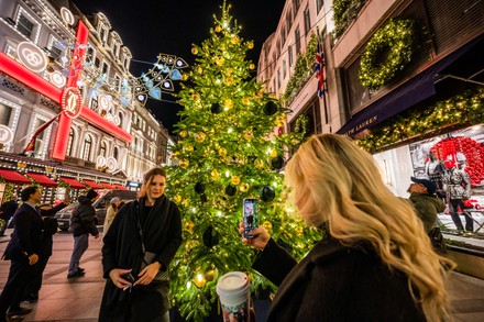 London, UK. 17th Nov, 2022. Taking selfies outside the Dior and LV stores -  Christmas lights are turned on above Bond Street and on the store fronts of  many of the luxury