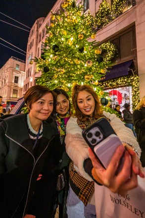 London, UK. 17th Nov, 2022. Taking selfies outside the Dior and LV stores -  Christmas lights are turned on above Bond Street and on the store fronts of  many of the luxury