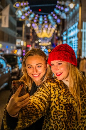 London, UK. 17th Nov, 2022. Taking selfies outside the Dior and LV stores -  Christmas lights are turned on above Bond Street and on the store fronts of  many of the luxury