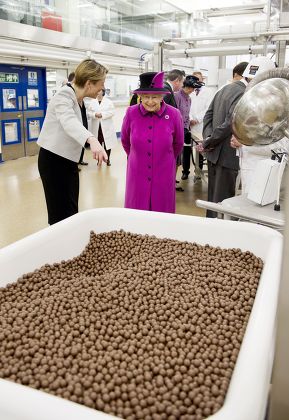 Fiona Dawson, President of Mars Chocolate UK shows Queen Elizabeth II a vat containing Maltesers chocolate sweets