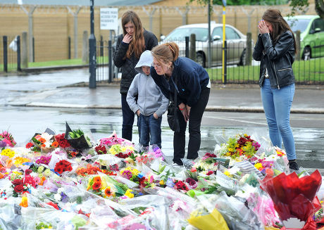 Woolwich residents fourteen years old Chloe Caulfield, 12 years old Emma Caulfield (L), their mother Nicola (C) and brother Ben lay some flowers near the entrance to Woolwich army barracks a short distance from the spot