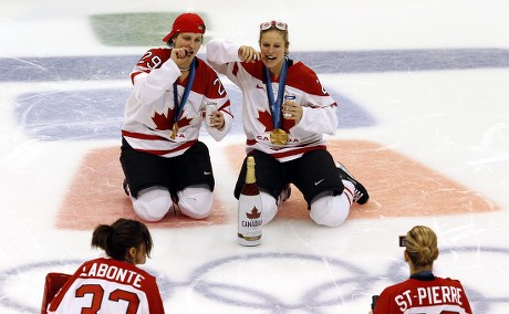 Canadian team players Marie-Philip Poulin (L) and Tessa Bonhomme (R)  celebrate smoking and drinking on the ice their victory over the USA, at  the end of the women ice hockey gold medal