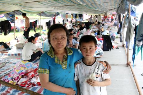 Refugee boy Zhou Kai and his mother Mao Xin Li, survivors of the chinese earthquake at a temporary roadside camp in Shifang