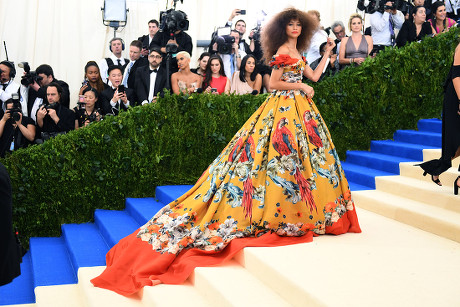 1 Met gala steps stairs wearing dolce & gabbana red color colored colour  coloured yellow white blue green floral print pattern patterned strapless  off shoulder neckline parrot bird floor long train dress