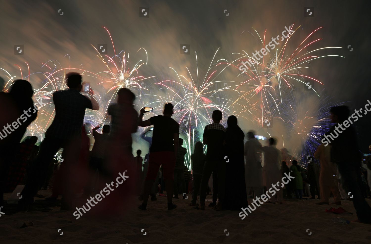 People Watch Fireworks Illuminate Sky Over Corniche Editorial