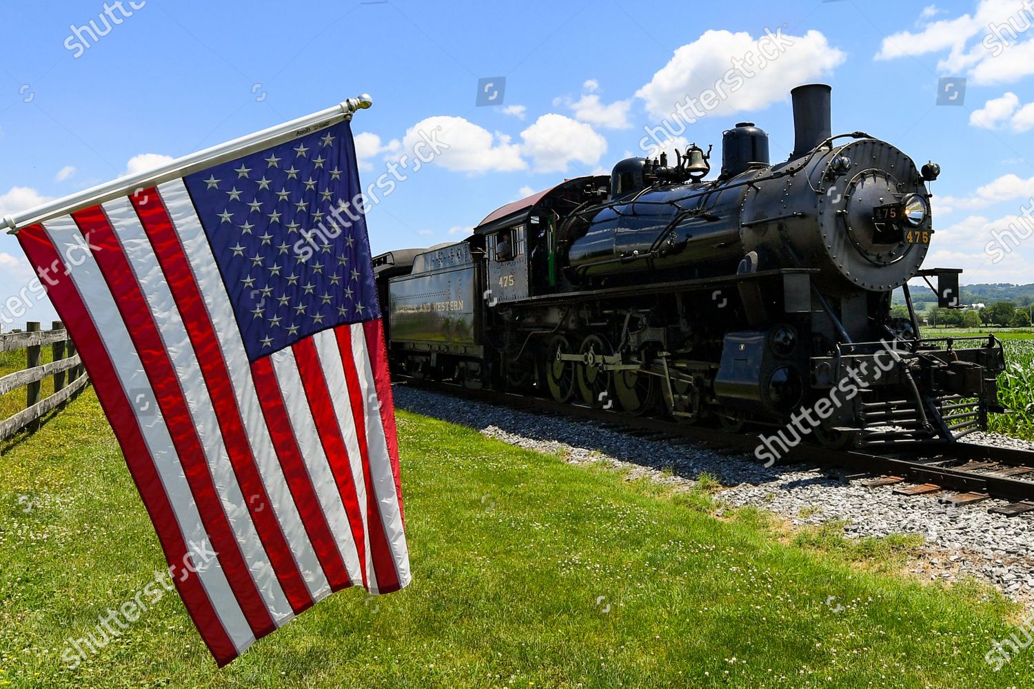 The Strasburg Railroad, Norfolk & Western, 475 steam locomotive passes an  American Flag during its return to the station on Monday, June, 29, 2020,  in Ronks, Pennsylvania. The Strasburg Railroad re-opened for