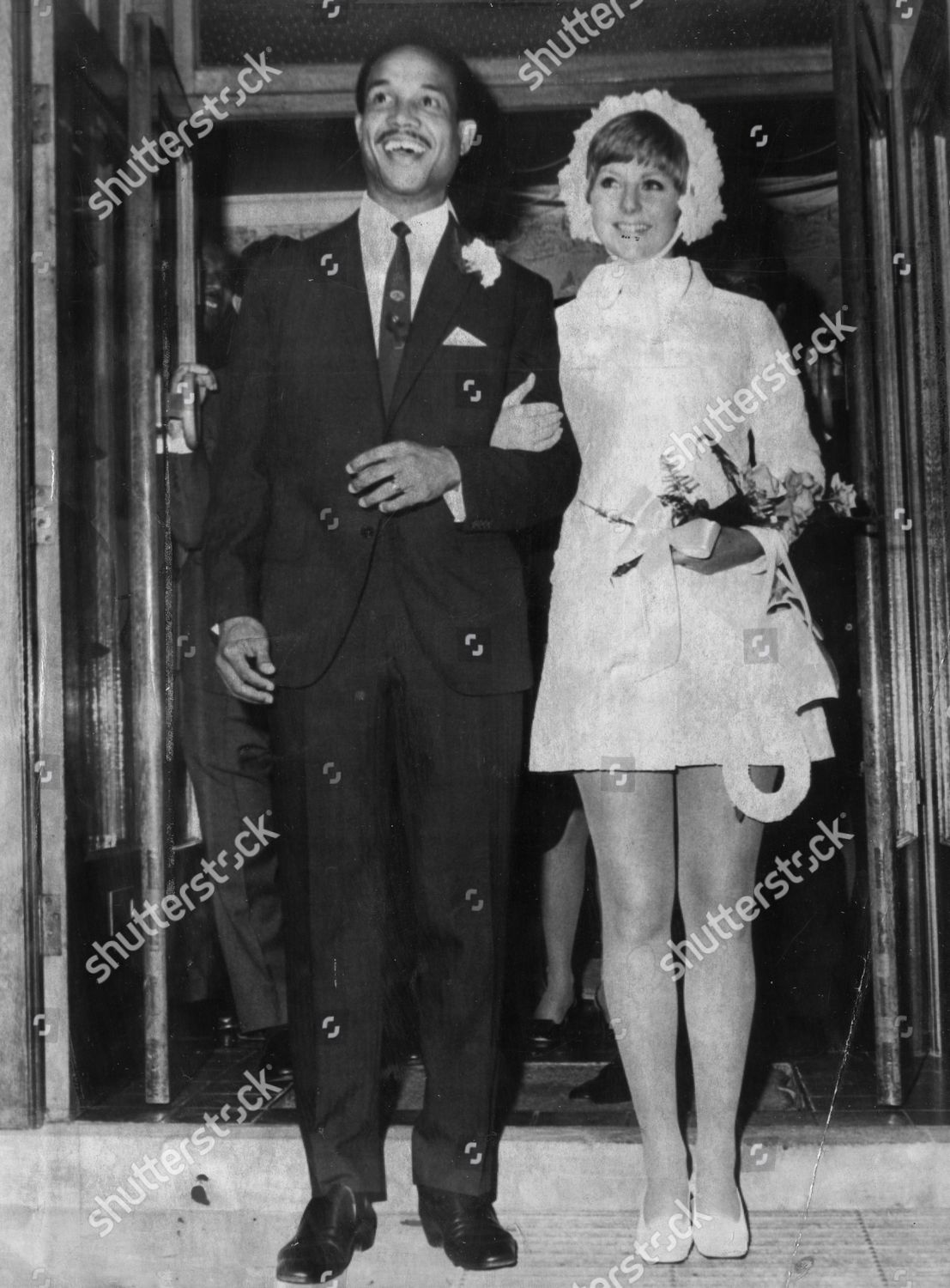 https://editorial01.shutterstock.com/wm-preview-1500/3029117a/9c79984b/sir-garry-garfield-sobers-and-lady-prudence-kirby-stand-arm-in-arm-on-the-steps-of-basford-registry-office-in-nottingham-after-their-wedding-ceremony-garry-wears-a-typical-smart-black-suit-whilst-his-bride-wears-a-short-white-coat-dress-with-white-shutterstock-editorial-3029117a.jpg