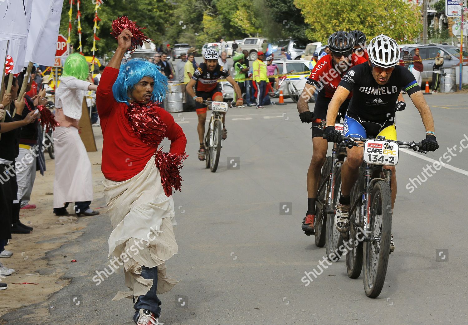 Riders Pedal Past Cross Dresser During Stage Editorial Stock Photo