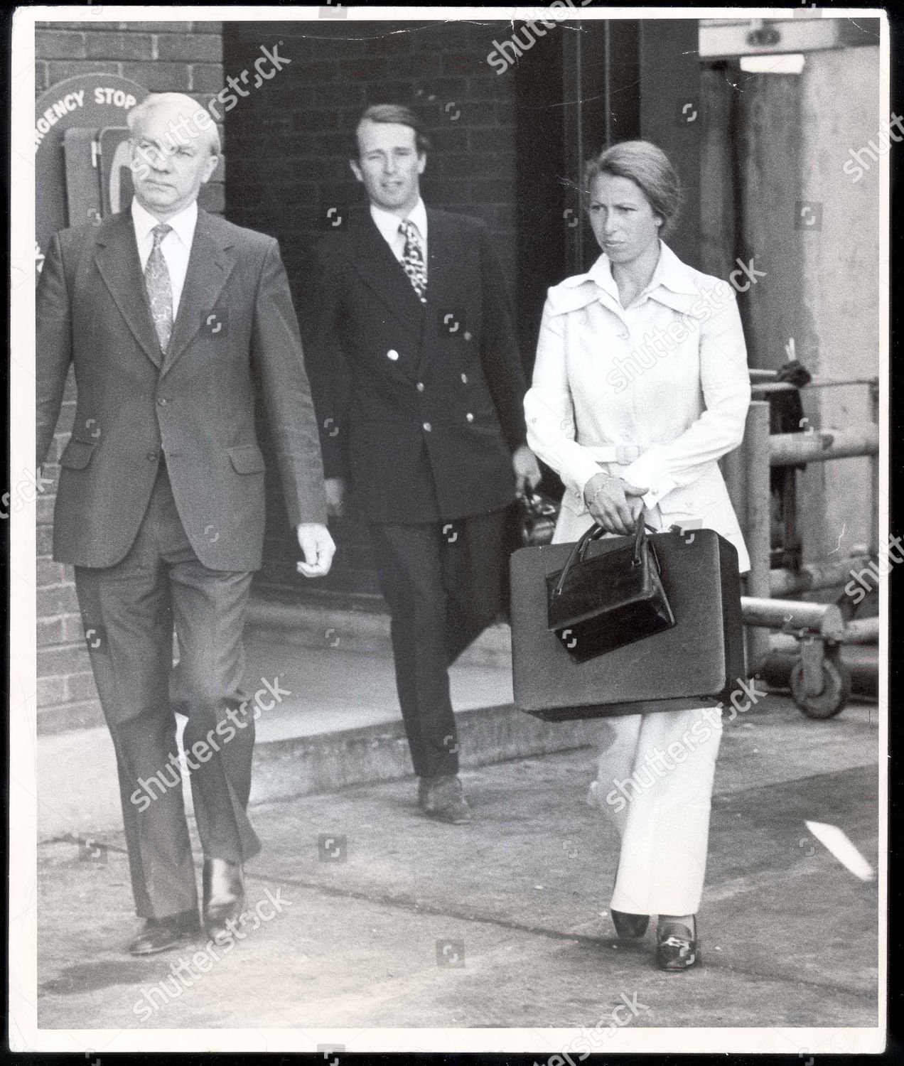 princess-anne-now-princess-royal-july-1975-wearing-a-safari-suit-princess-anne-lifts-a-suitcase-into-the-boot-of-a-car-watched-by-her-husband-capt-mark-phillips-shortly-after-their-arrival-today-from-boston-mass-they-have-been-in-america-taking-p-shutterstock-editorial-890968a.jpg